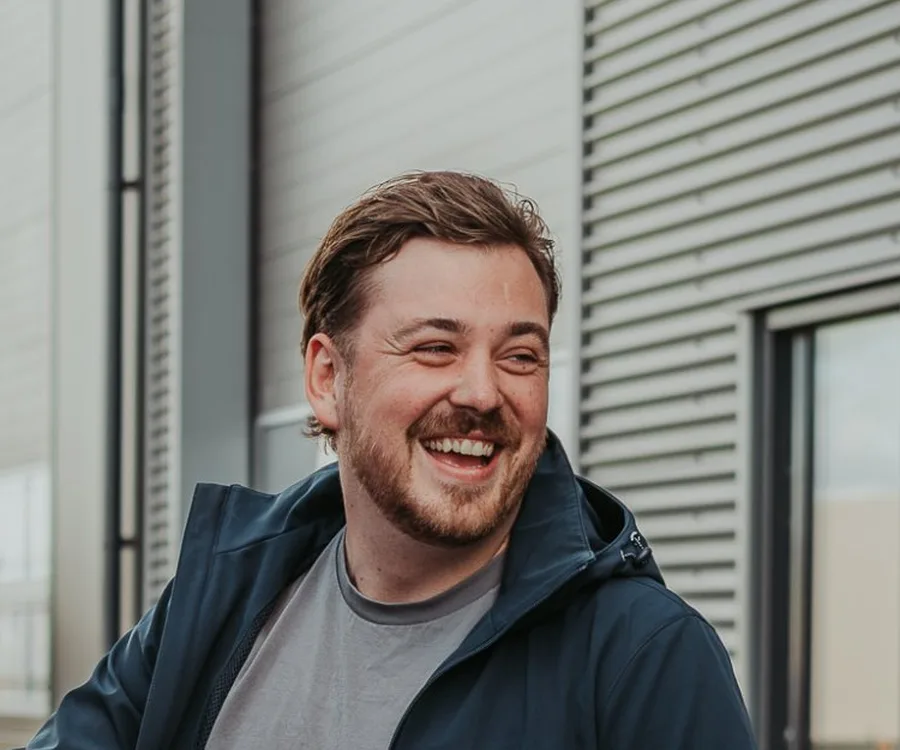 Portret van Davey, lachend, buiten voor een bedrijfspand